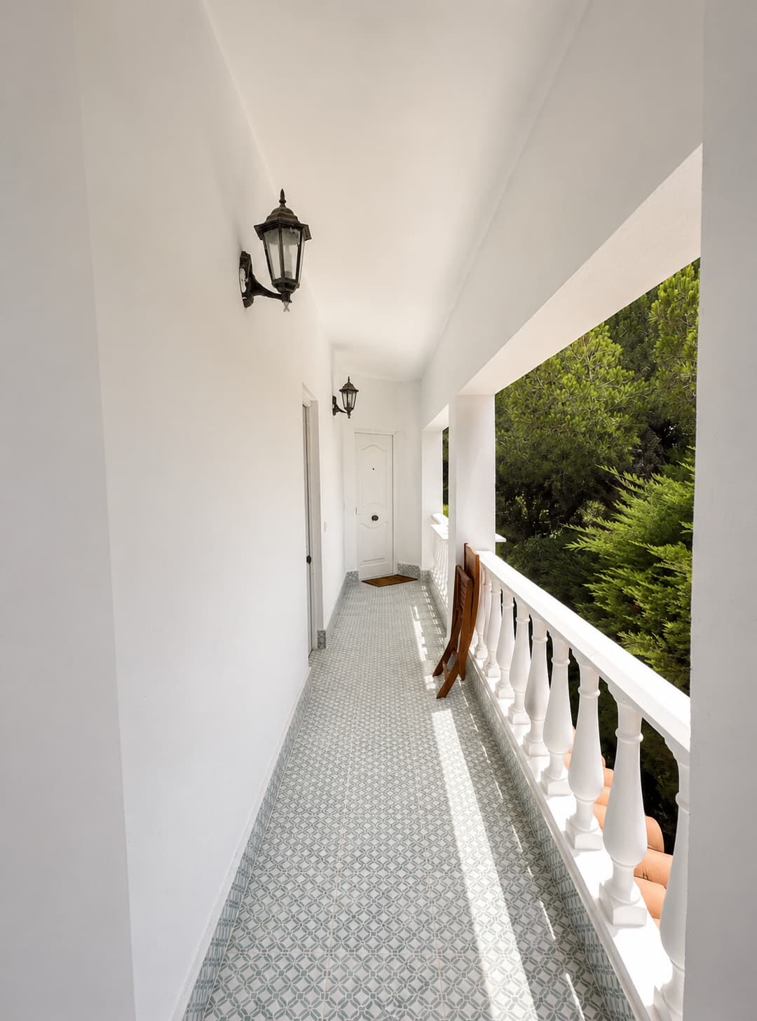 A white gallery with patterned tiles, looking into the pines